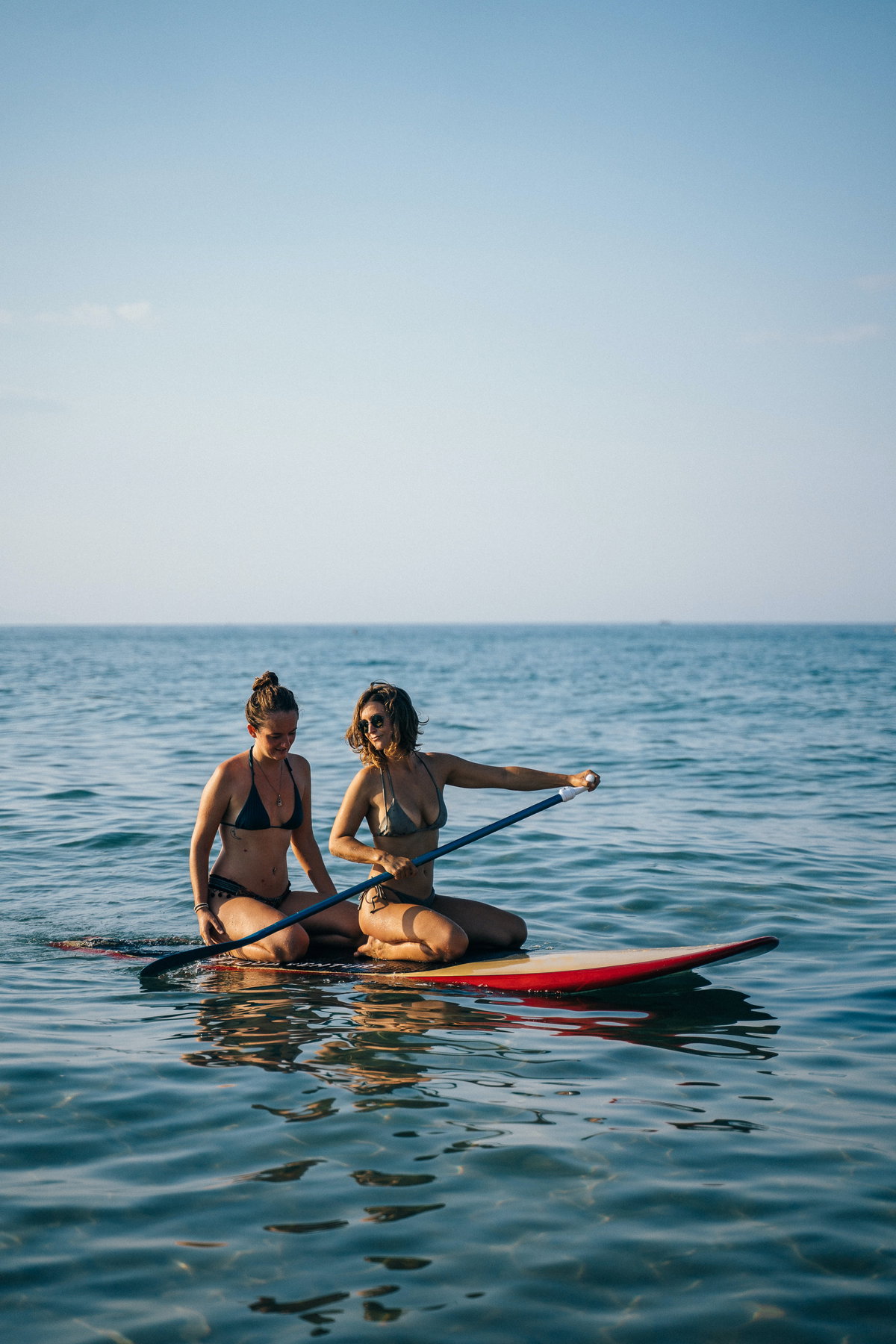 Zwei Frauen sitzen auf Surfboard im Meer