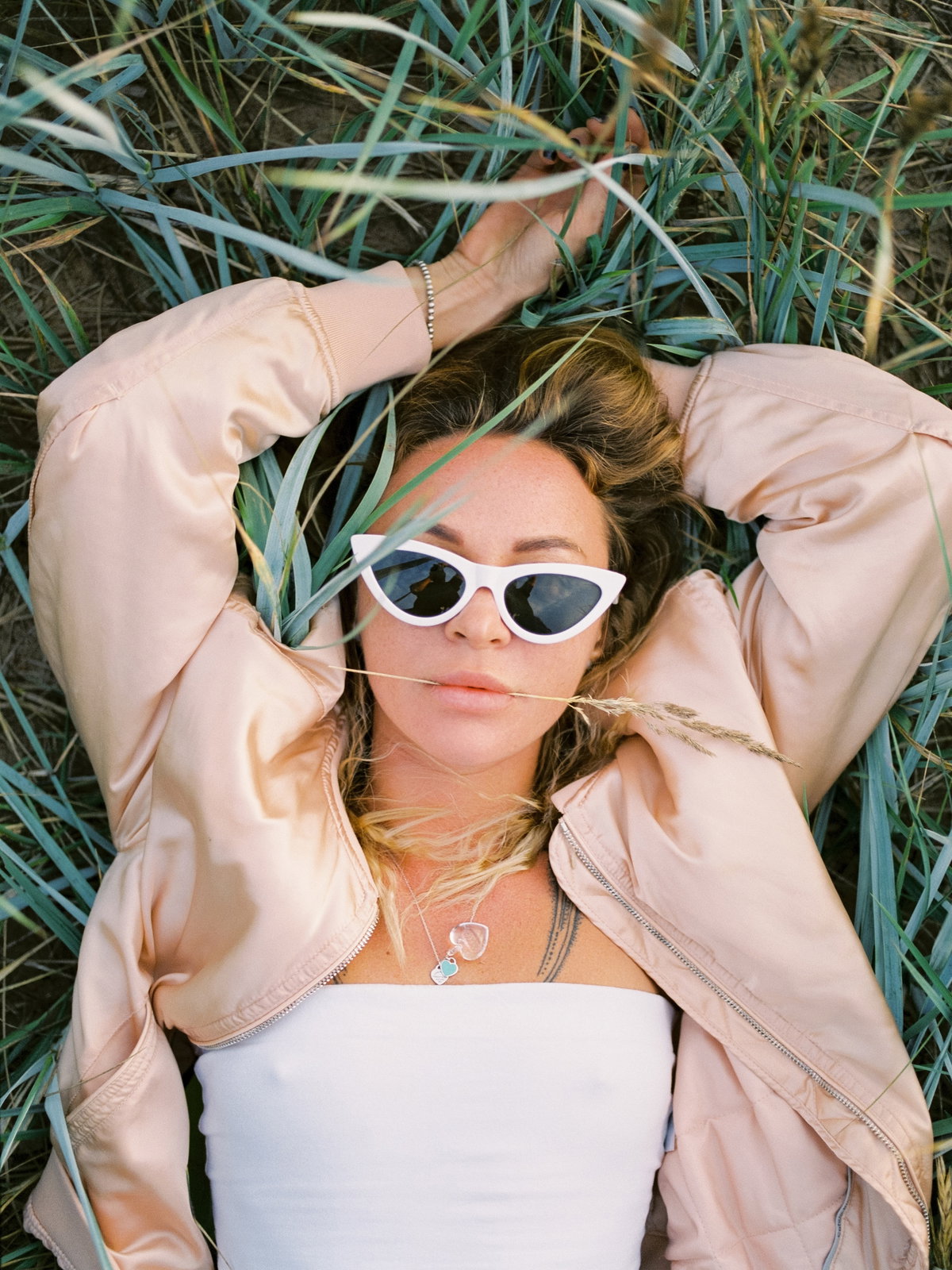 Frau mit Sonnenbrille liegt im Gras
