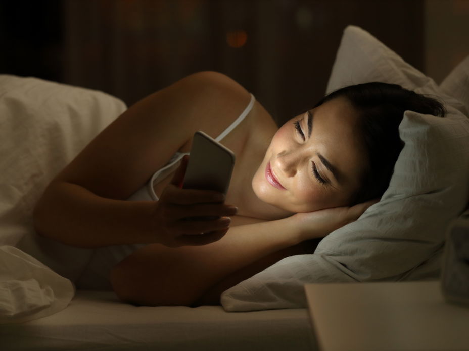 Sexting: Frau mit Handy im Bett