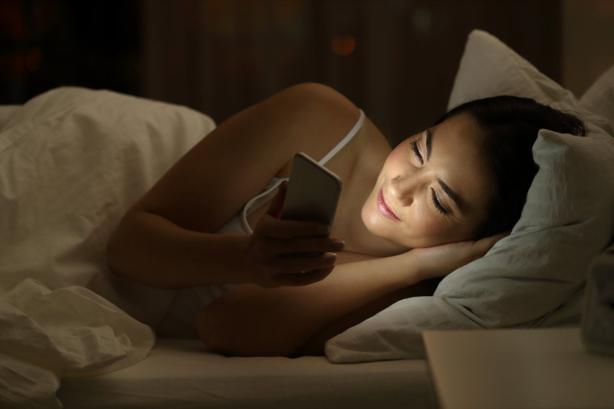 Sexting: Frau mit Handy im Bett