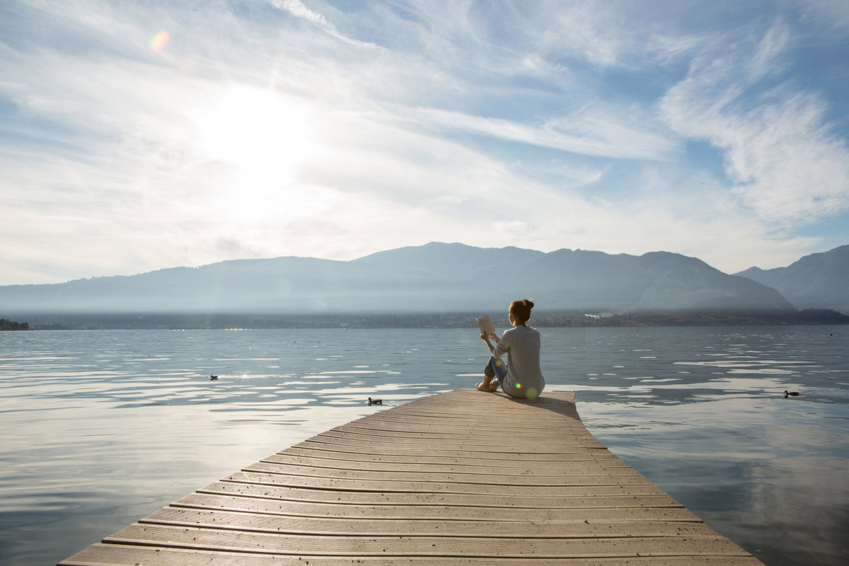 Frau sitzt nuit Buch am See
