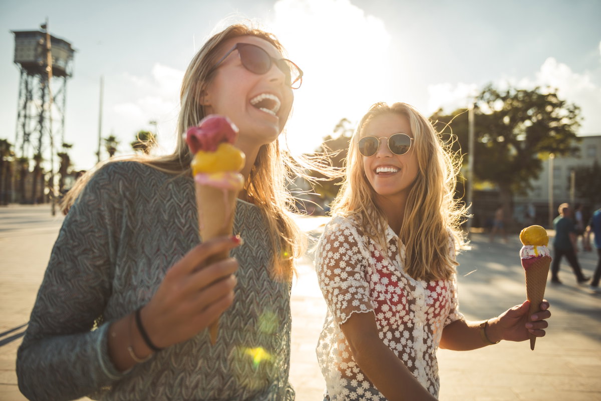 Zwei Freundinnen lachen gemeinsam und essen Eis
