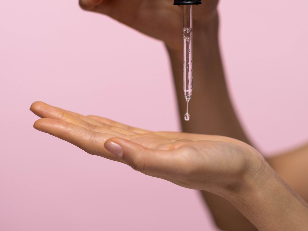 Hände tragen Serum auf