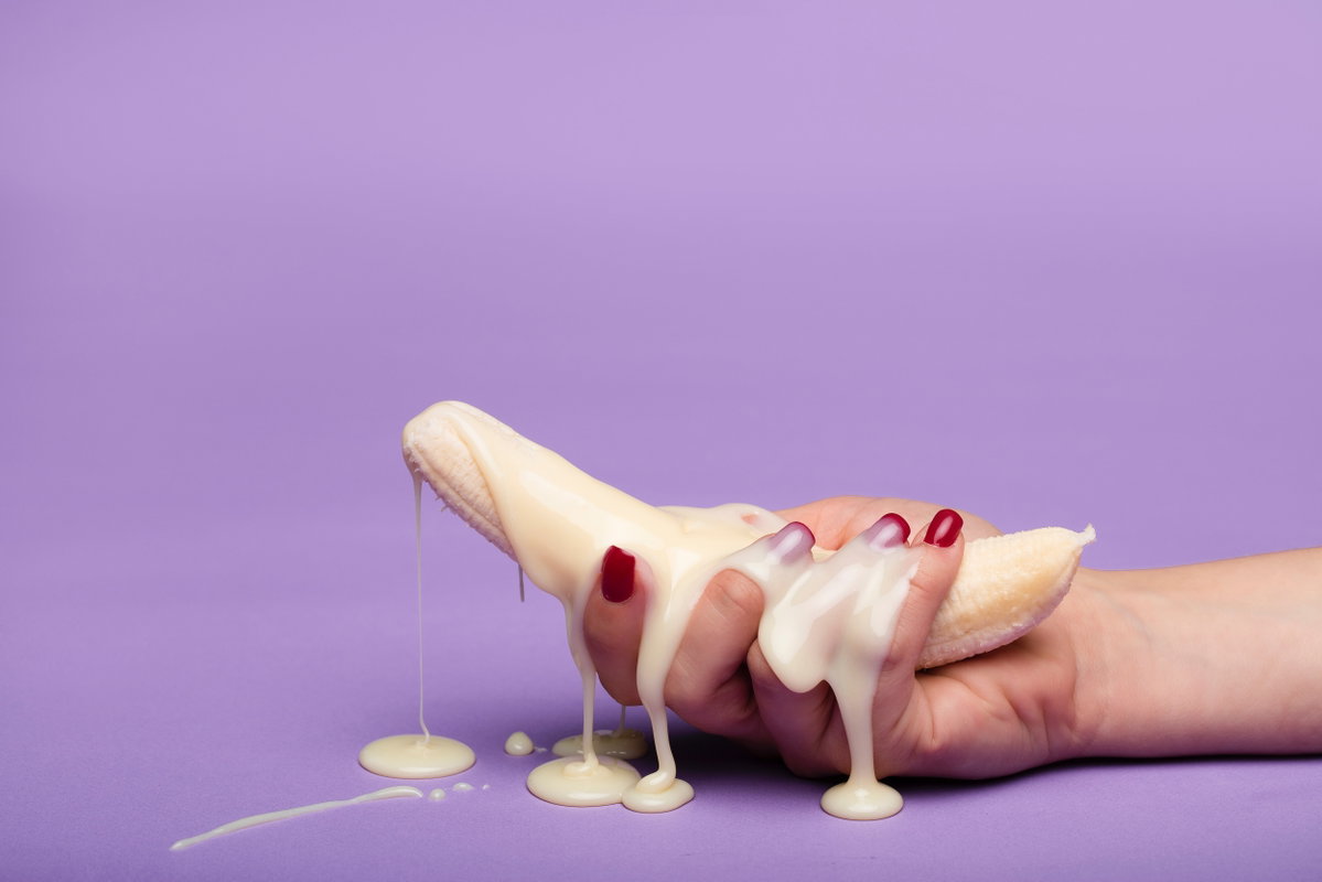 Banane in Hand und weiße Creme