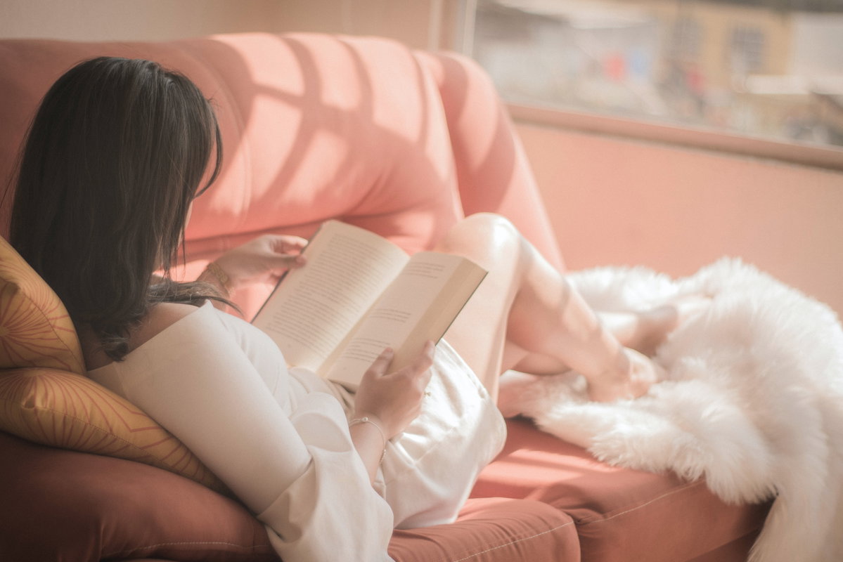 Frau liest Buch auf dem Sofa