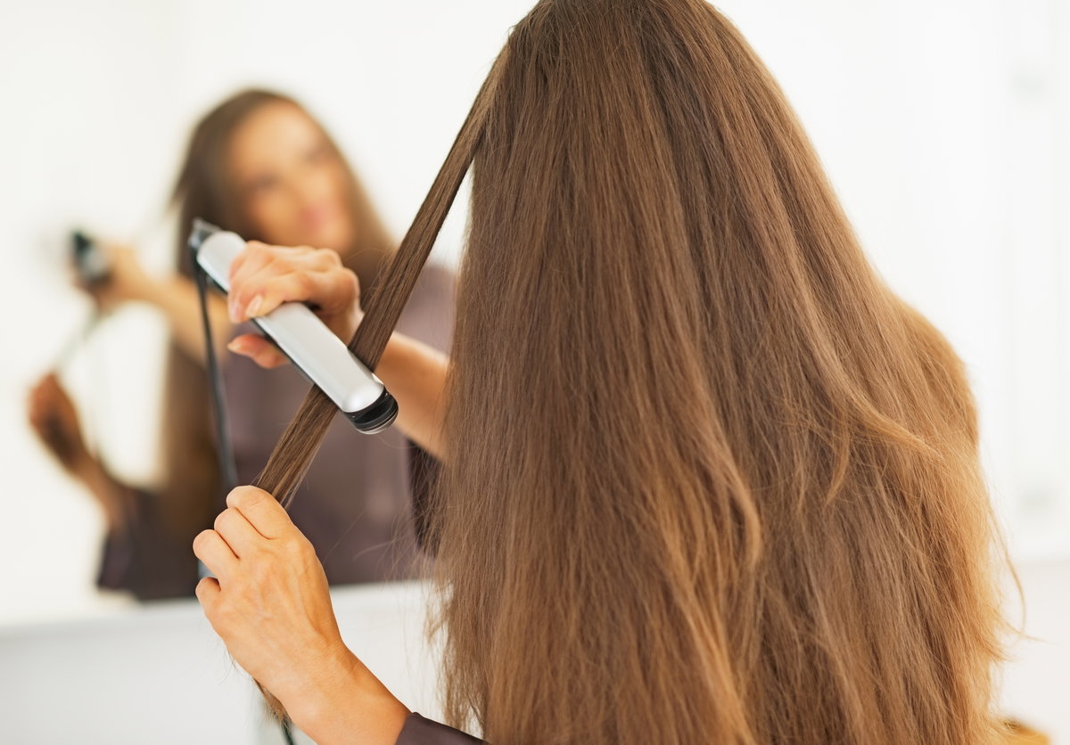 Frau glättet sich Haare