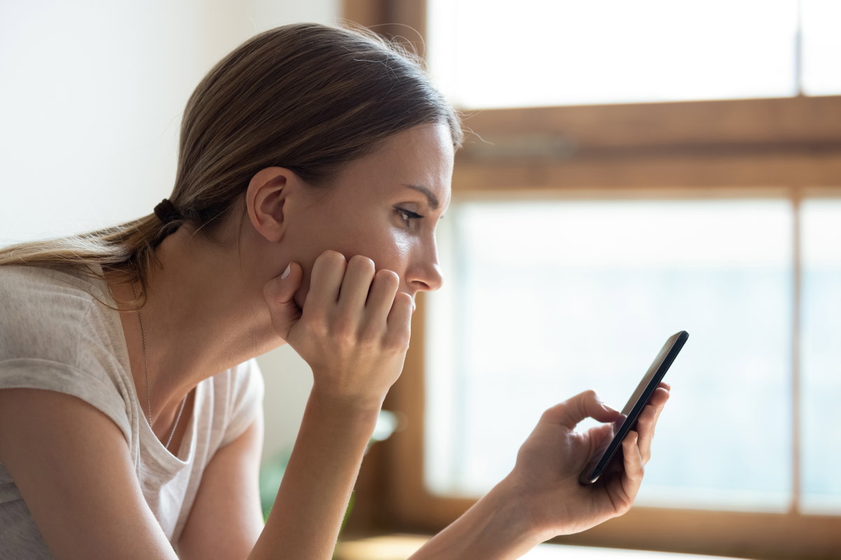 Frau schaut traurig auf Handy