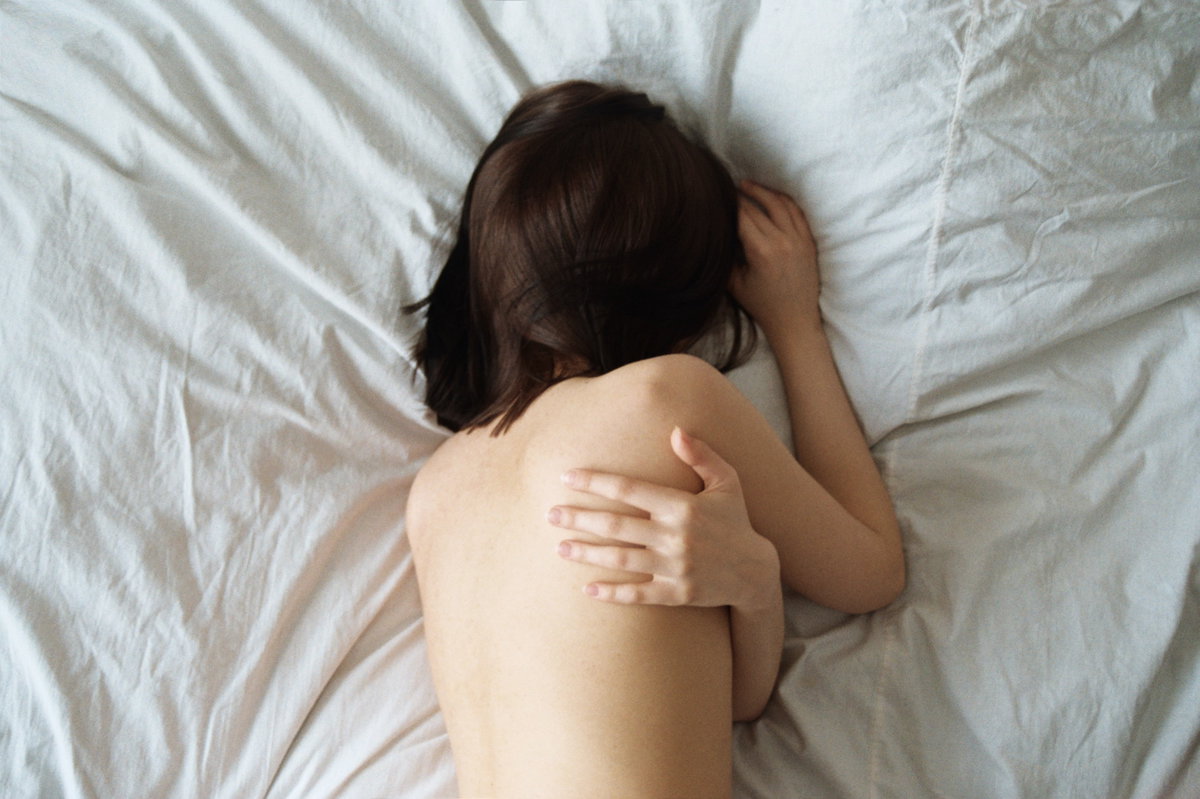Frau schläft nackt im Bett