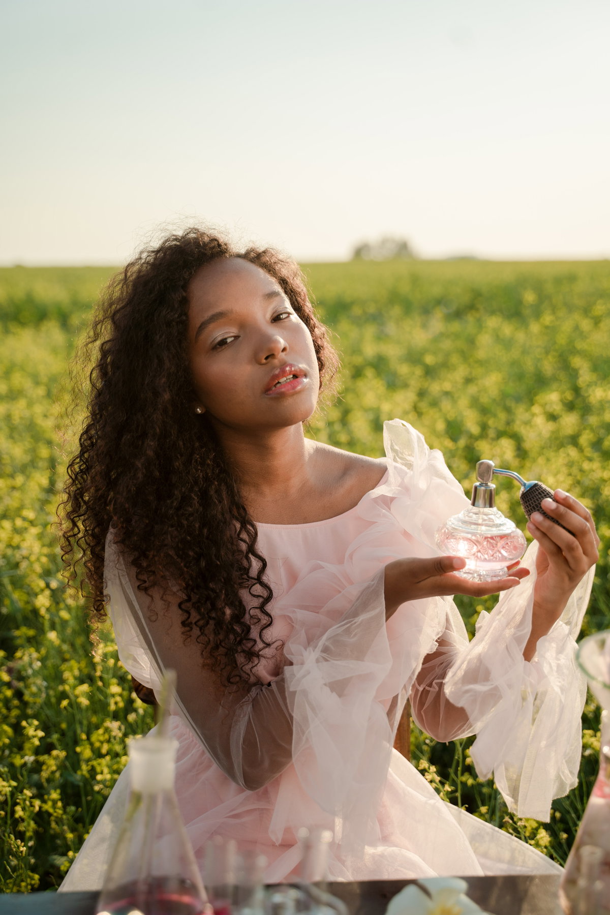 Frau auf Feld mit Parfum in der Hand
