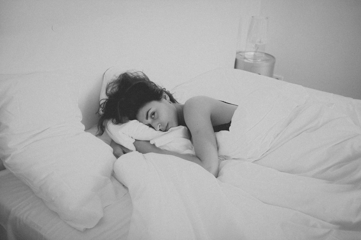 Frau liegt traurig im Bett