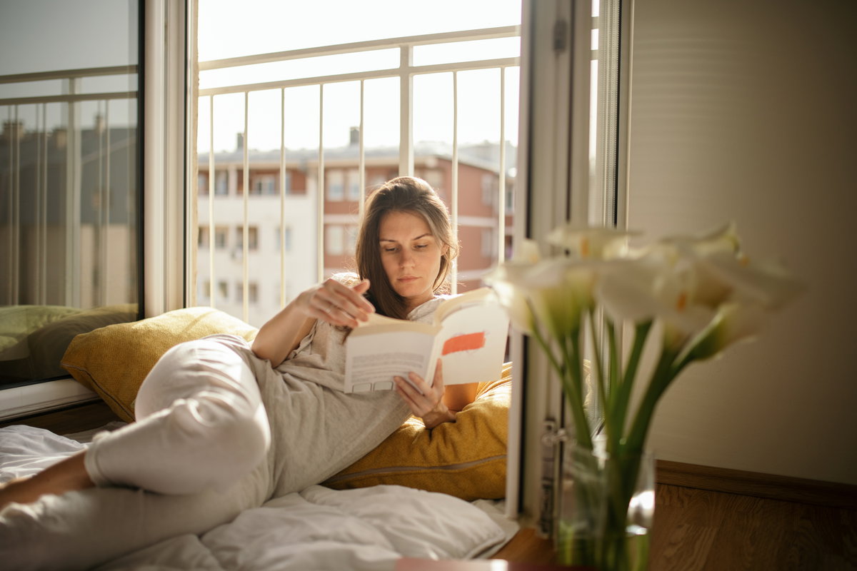 Frau liest Buch am Fenster