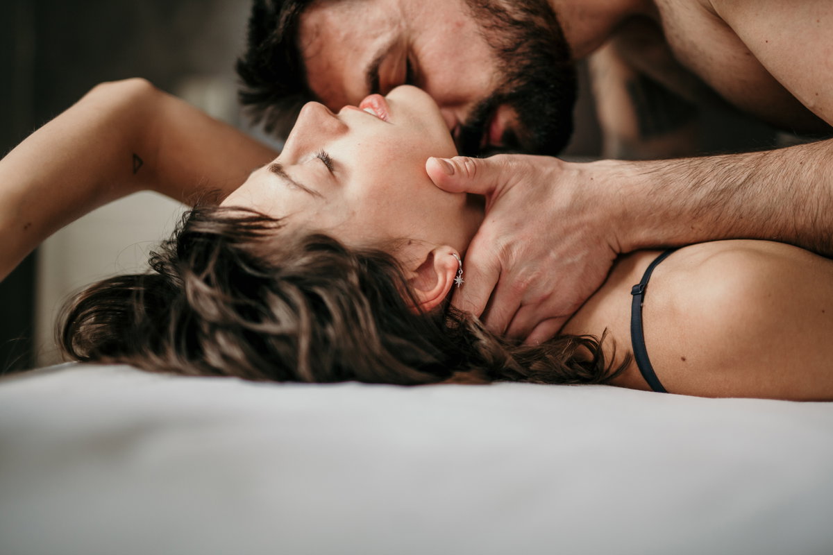 Mann küsst Hals der Frau im Bett