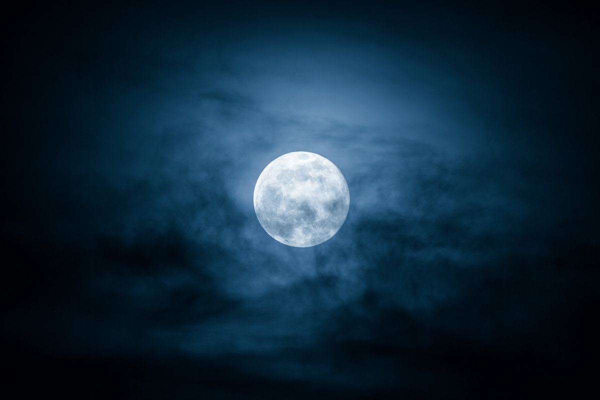 Der Vollmond steht am Himmel hinter Wolken