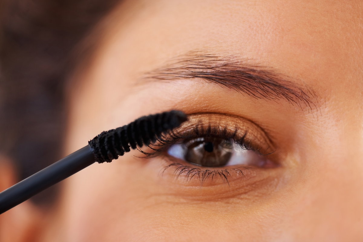 Frau trägt Mascara auf mit braunen Augen