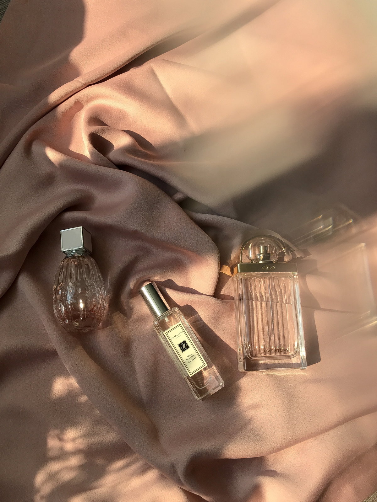 drei Parfums liegen auf einem Tuch