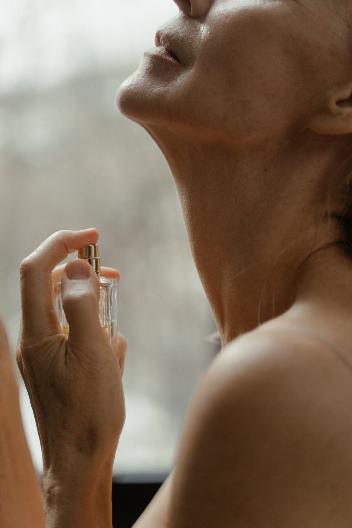 Frau sprüht Parfum auf
