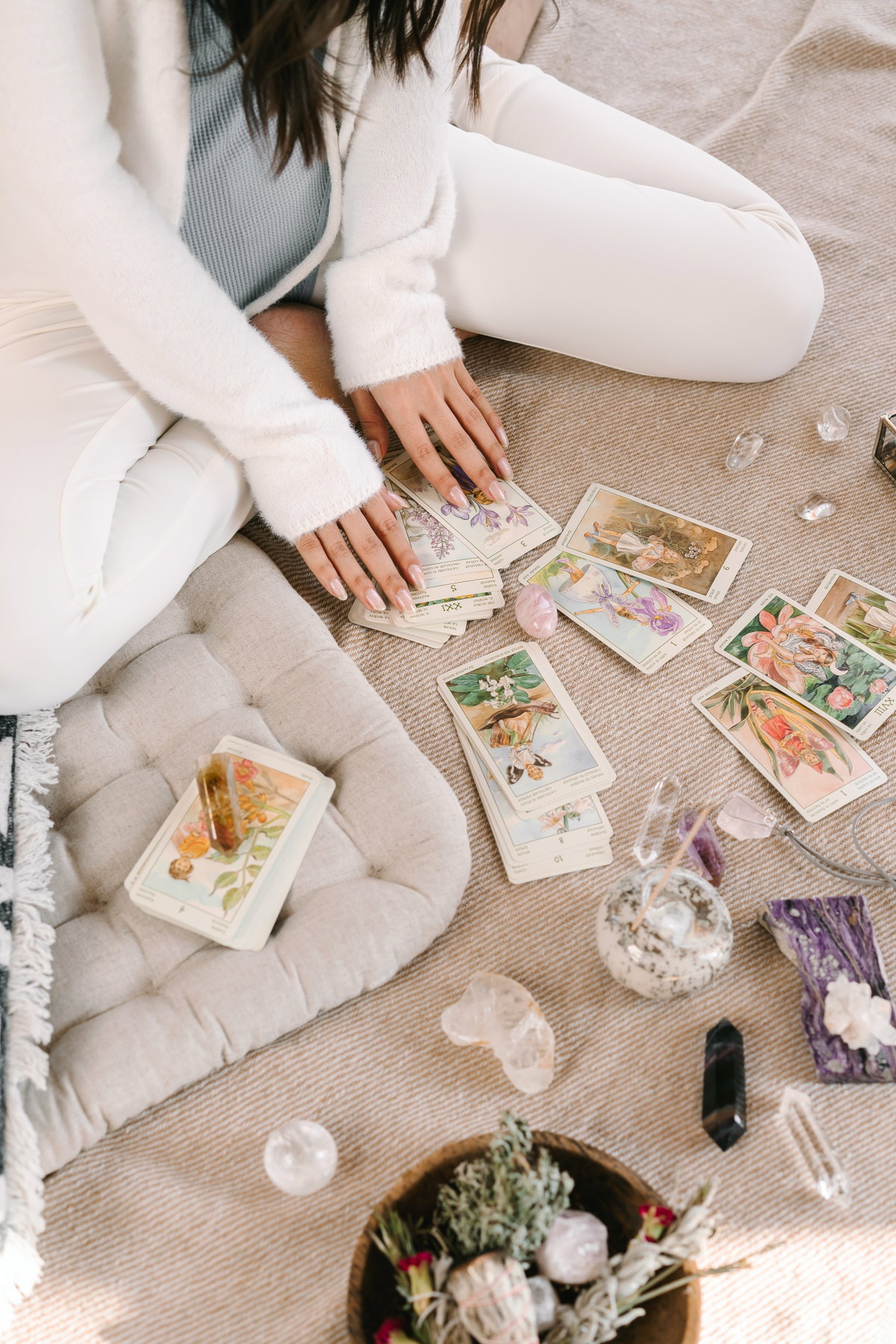 Frau hat vor sich Tarot-Karten und Kristalle liegen