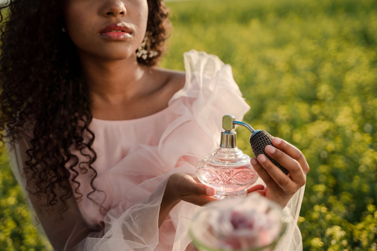 Frau hält rosa Parfum Flakon in der Hand