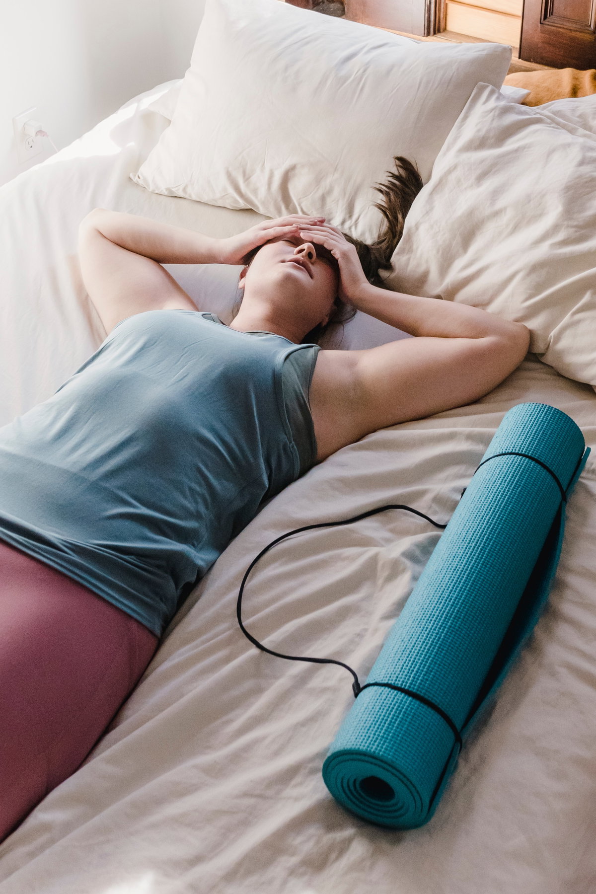 Frau liegt in Sportkleidung auf dem Bett