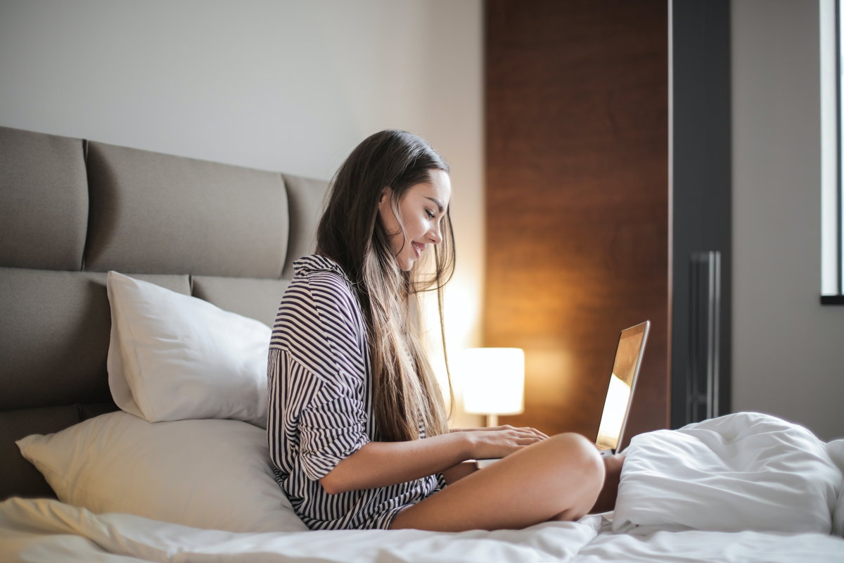 Junge Frau am Laptop im Bett