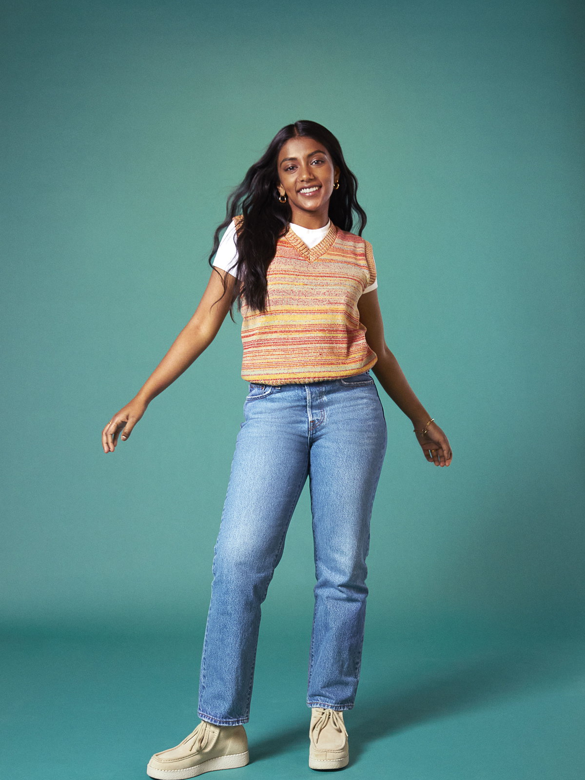 Gute Laune ist dank dieses bunten Jeans-Looks mit simplem weißem Shirt, Strickpullunder und der "Wedgie Straight" aus der Kapsel-Kollektion von Levi's® x Charithra Chandran garantiert.