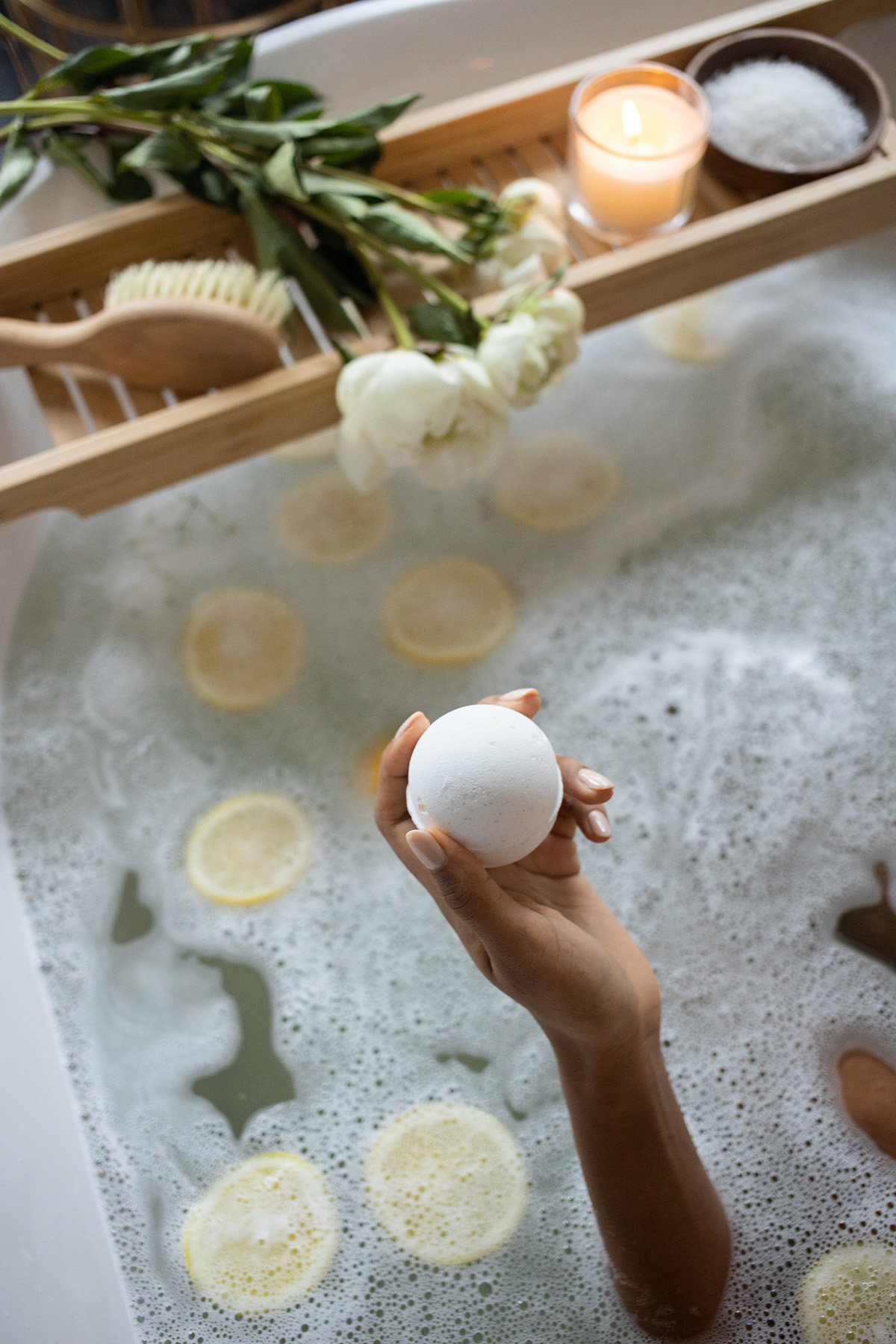 Frau hält Badekugel in der Badewanne