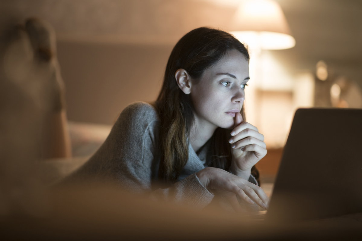 Junge Frau abends vor Laptop im Bett