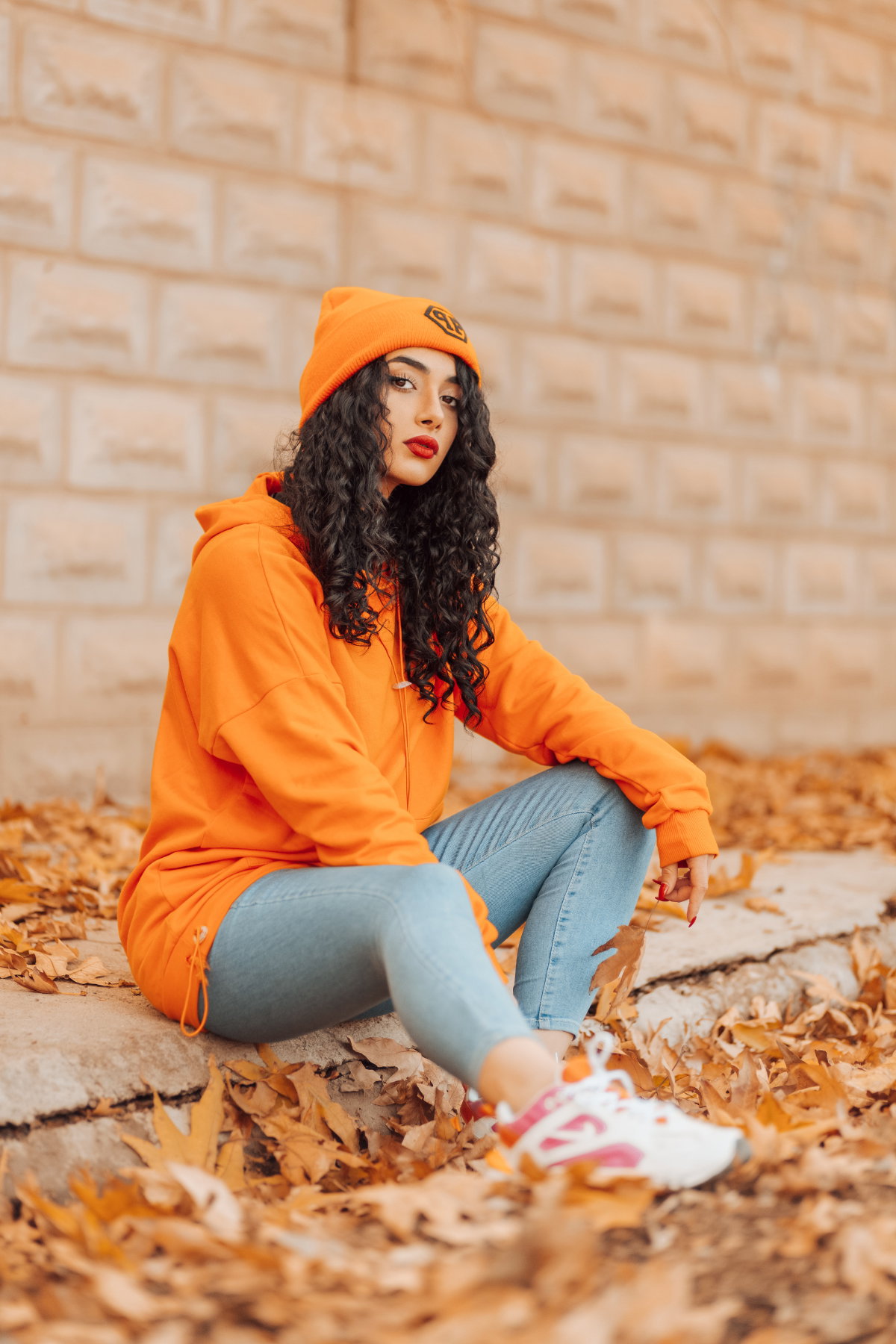 Frau in orange sitzt auf dem Gehweg