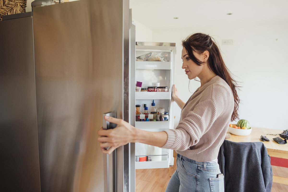 Frau schaut in den Kühlschrank