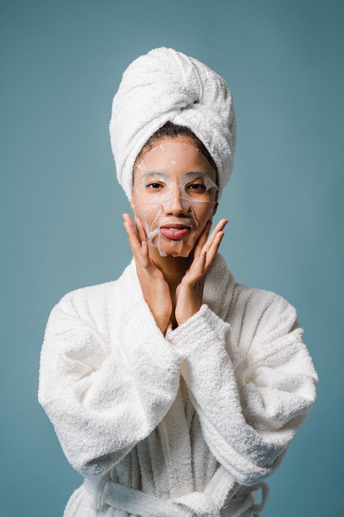 Frau im Bademantel mit Gesichtsmaske