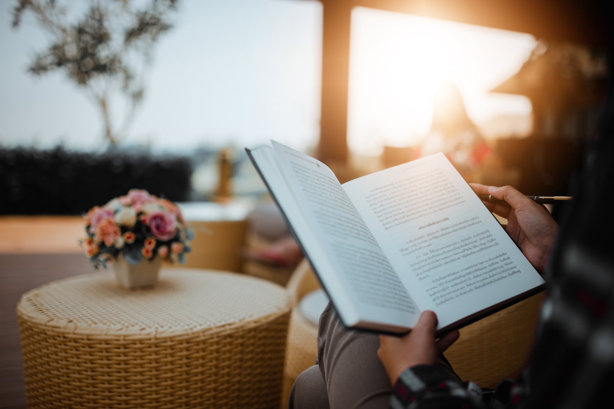 Person liest Buch auf Balkon