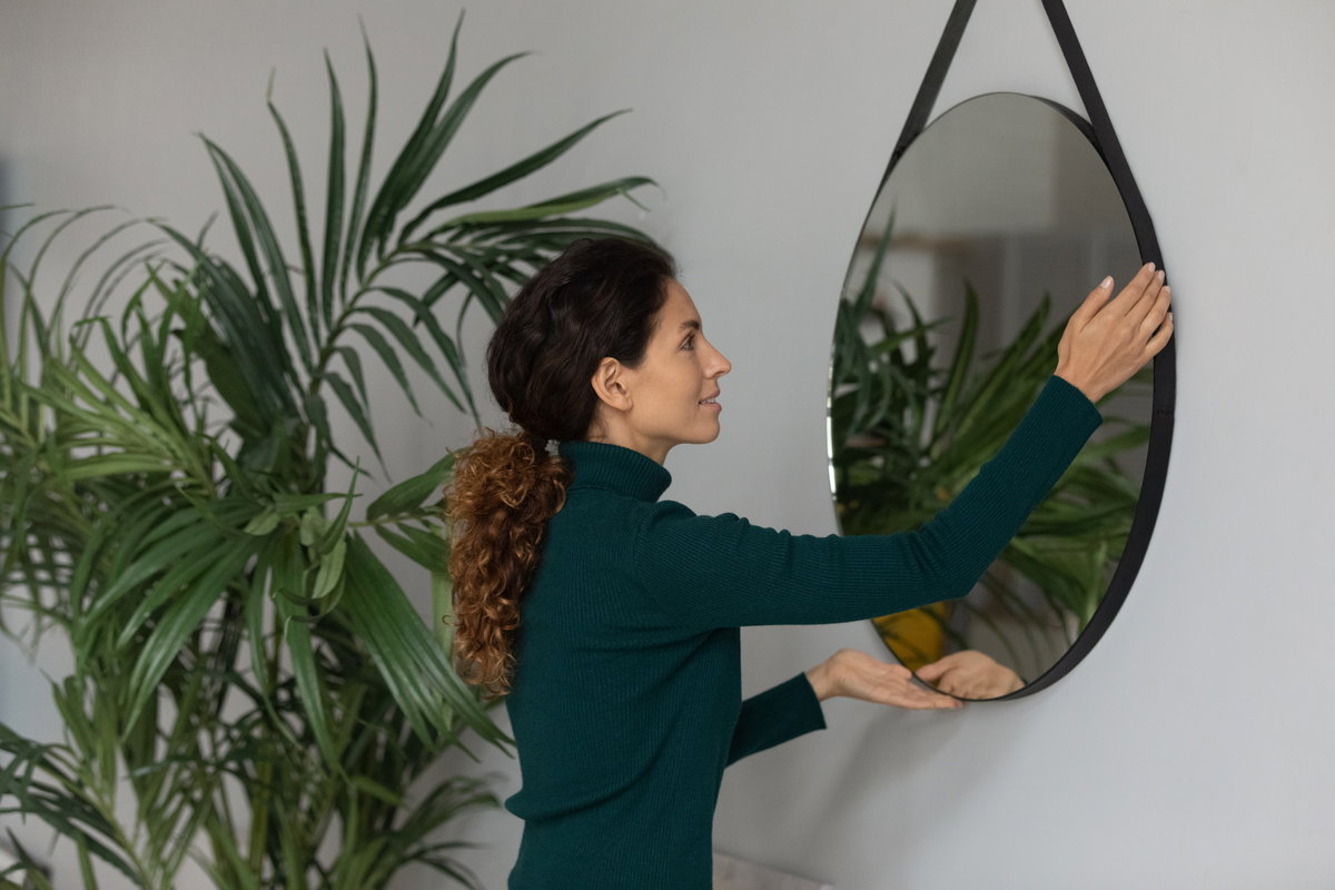 Frau hängt Spiegel an die Wand