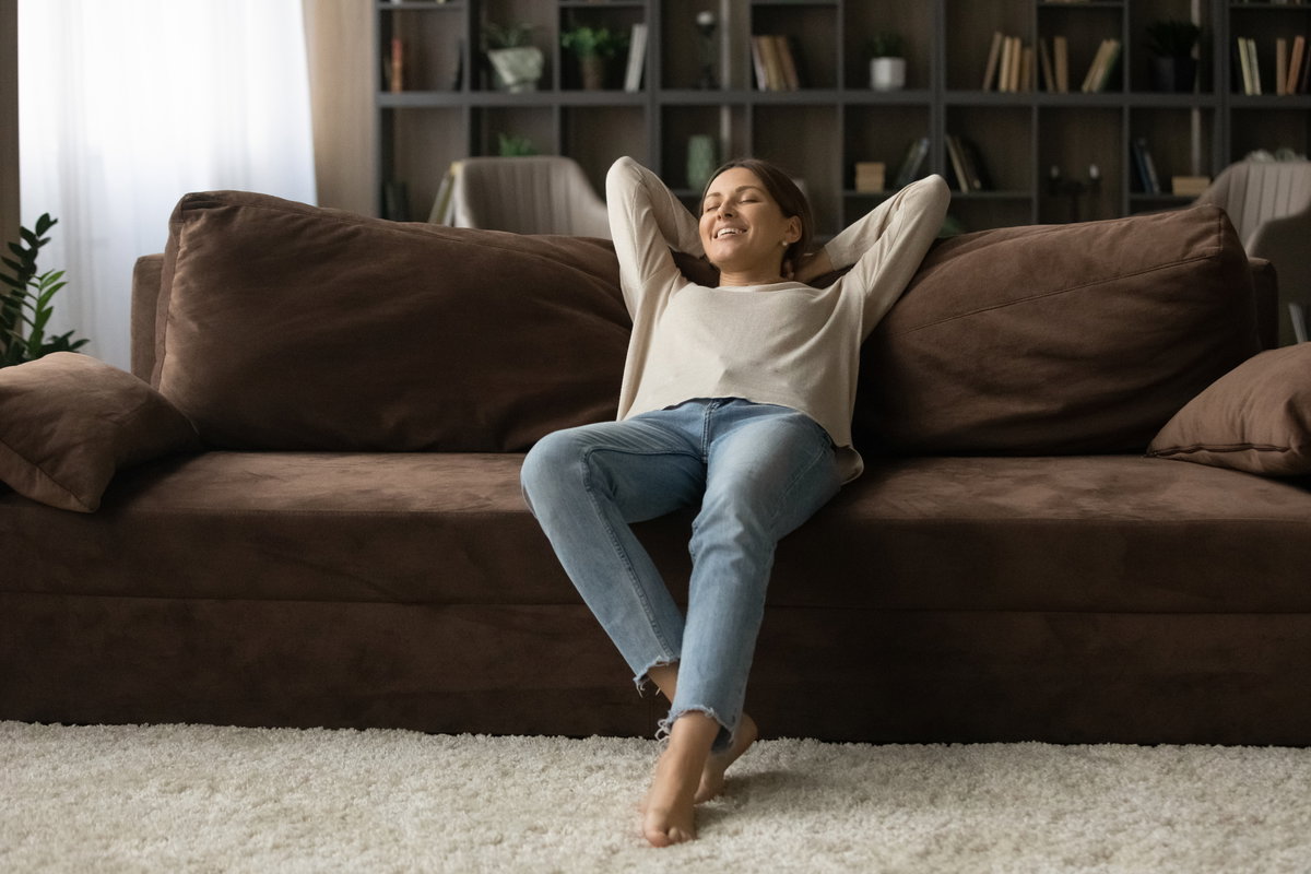 Junge Frau auf Sofa in kleiner Wohnung