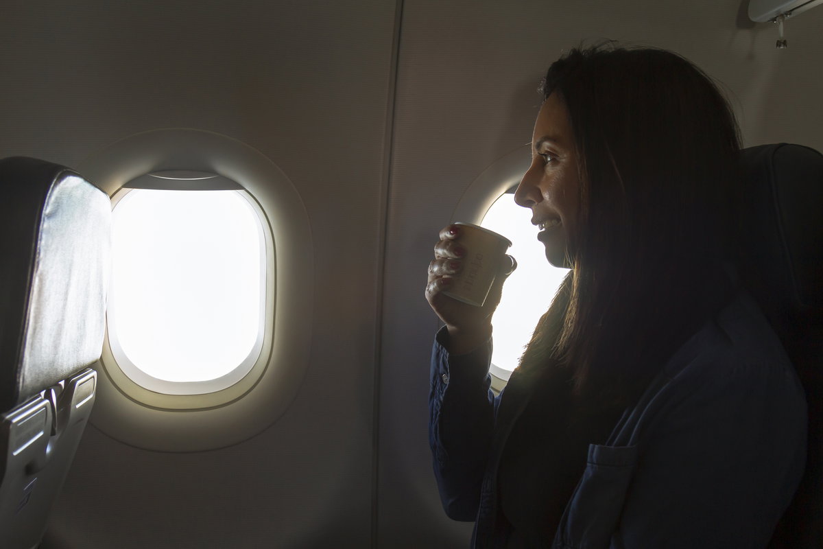 Frau trinkt Kaffee im Flugzeug