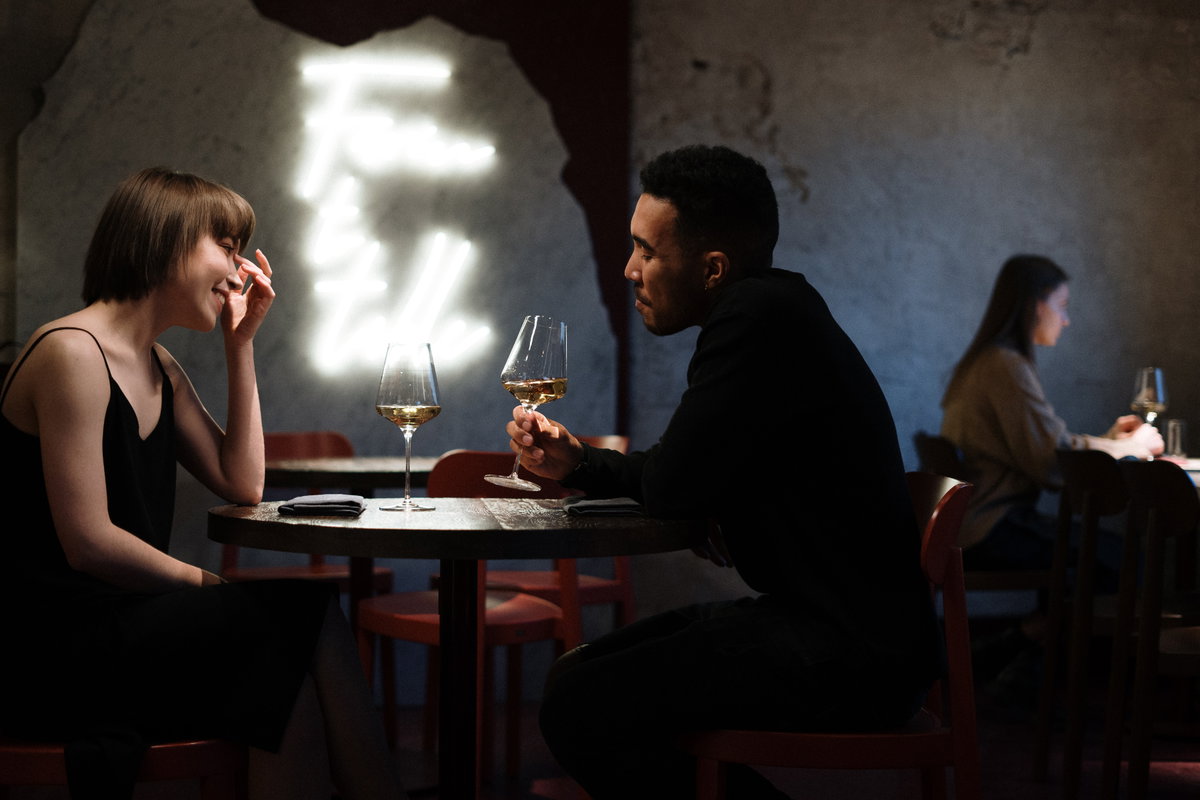 Paar beim ersten Date sitzt an einem Tisch und trinkt Wein.