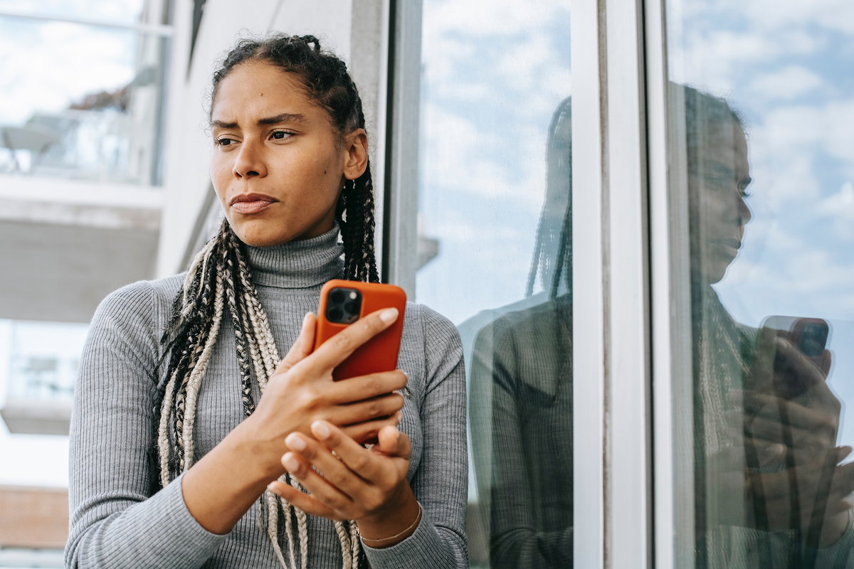 Frau hält ein Handy in der Hand und guckt traurig