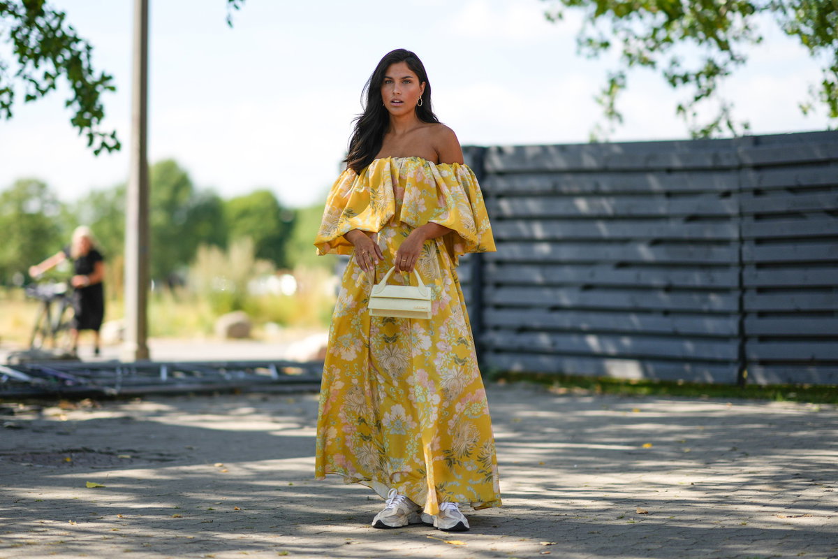 Frau im floralen Maxi-Kleid mit Sneakern