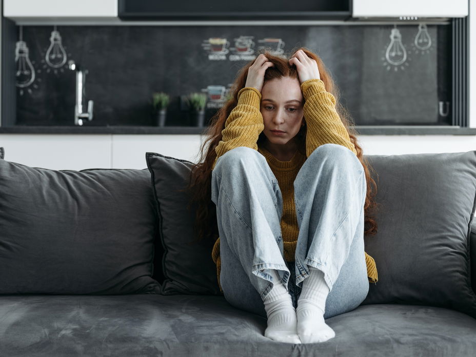 Frau sitzt gestresst auf dem Sofa