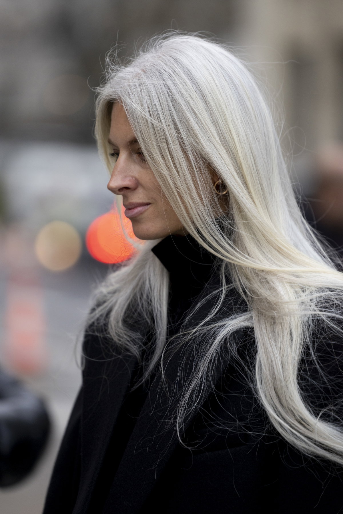 Frau trägt schwarzen Mantel und graue Haare mit Fox Cut
