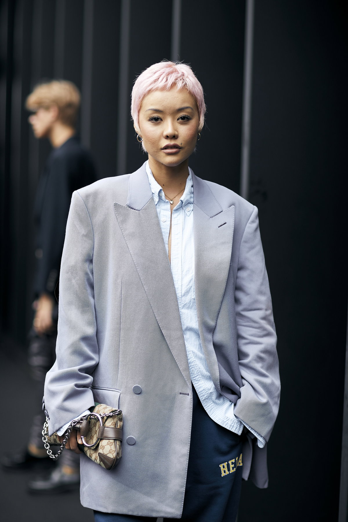 Frau trägt grauen Blazer auf der Mailand Fashion Week Streetstyle plus pinken Pixie Cut Frisur