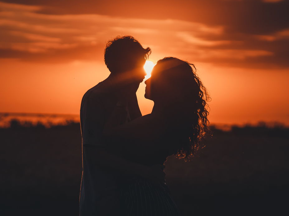 Mann und Frau umarmen sich mit Sonnenuntergang im Hintergrund