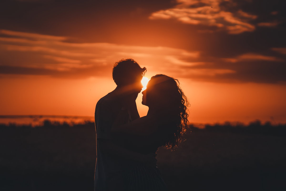Mann und Frau umarmen sich mit Sonnenuntergang im Hintergrund