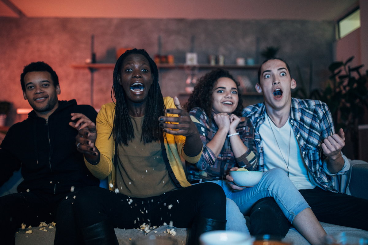 Gruppe von Freunden guckt Fernsehen und erschreckt sich