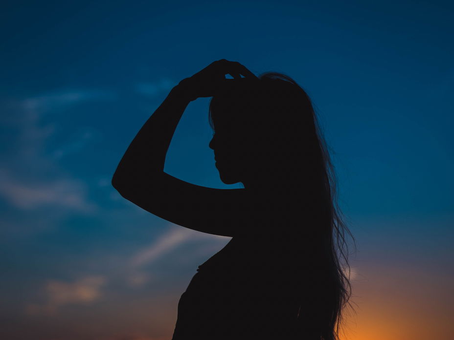 Silhouette einer Frau mit langen Haaren in der Dämmerung