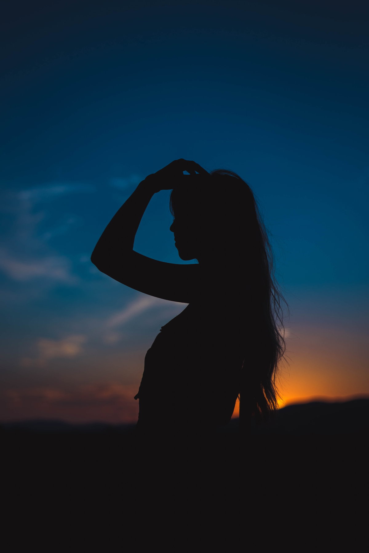 Silhouette einer Frau mit langen Haaren in der Dämmerung