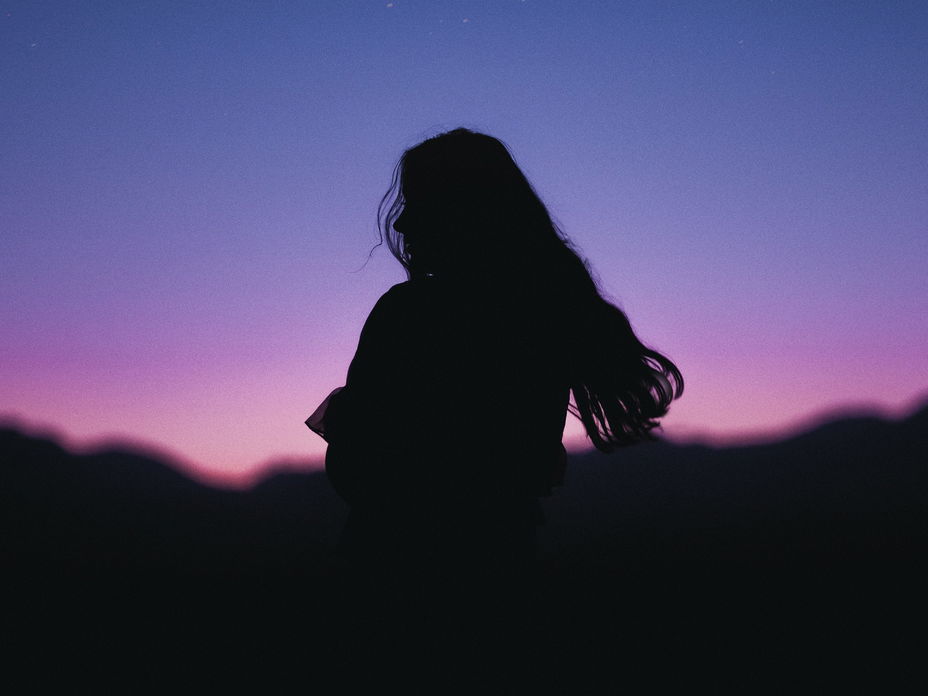 Silhouette einer Frau mit langen Haaren in der Nacht
