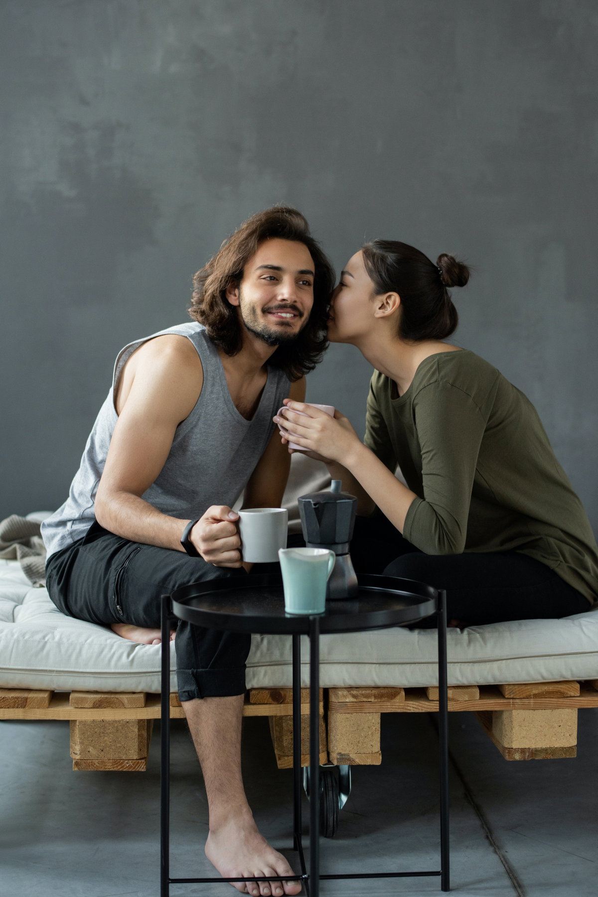 Mann und Frau sitzen auf einem Bett und trinken Kaffee