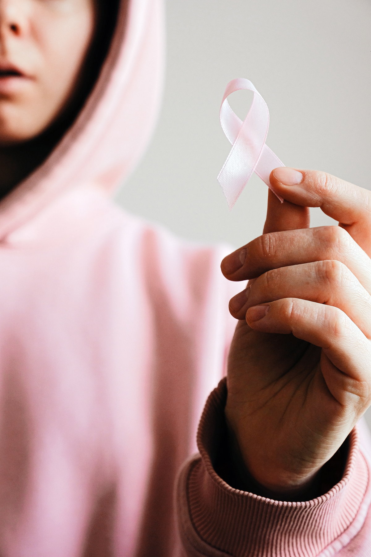 Frau mit pinkem Hoodie hält eine pinke Schleife in der Hand