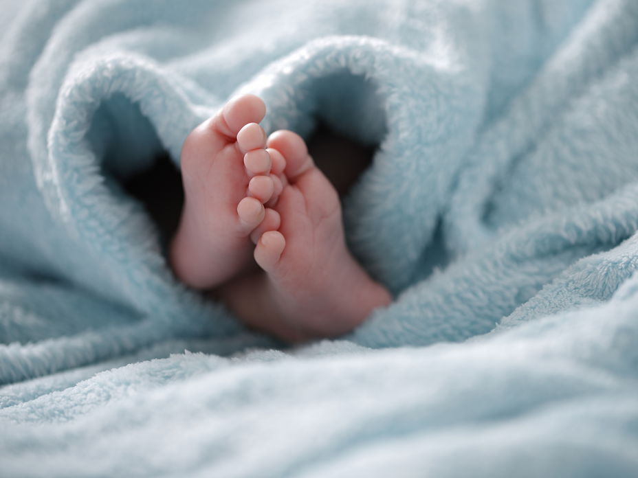 Babyfüße unter einer hellblauen Decke