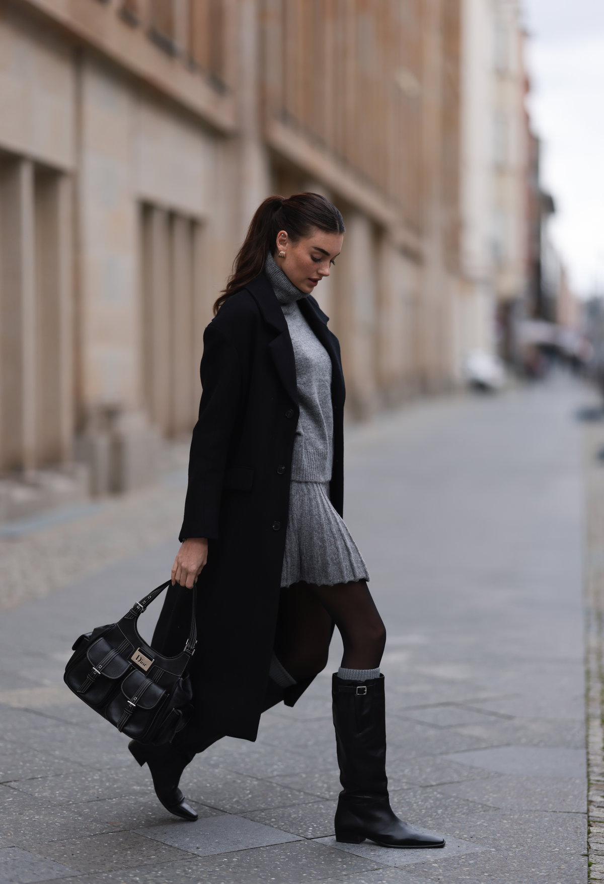 Frau trägt Stiefel und Dior-Tasche